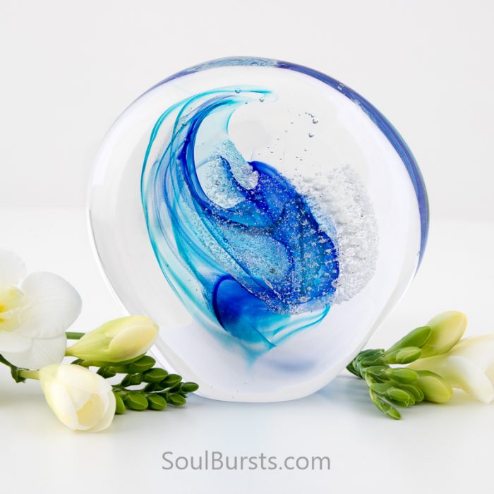 Blown glass piece with strands of royal blue and turquoise running through it