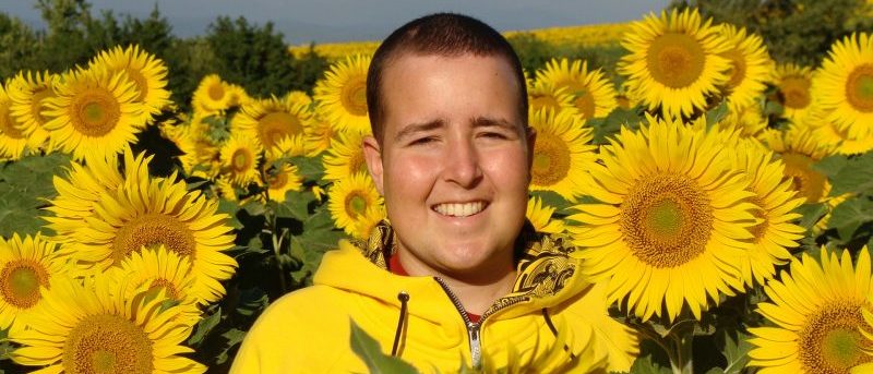 Jimmy standing in a field of sunflowers; only his head and shoulders are visible