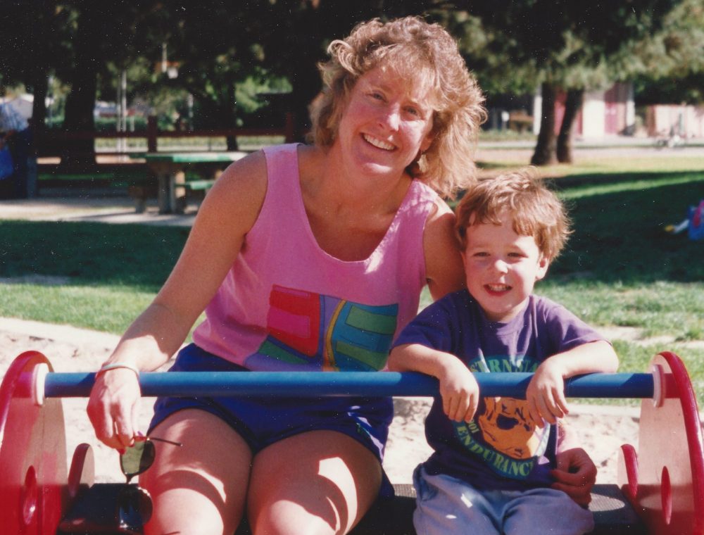 Margo on the left in a pink shirt sitting next to Jimmy, age 3, wearing a purple shirt in the park