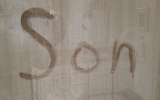 The word Son is written in steam on a glass shower door