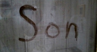 The word Son is written in steam on a glass shower door