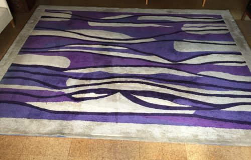 V'Soske rug -- white rug with purple, black and white stripes of varying widths and varying shades of purple