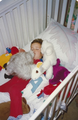 Jimmy asleep in his crib surrounded by wearing a red onsie