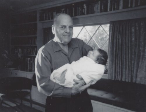 Dad holding me in the library of the house on Hurst. Black and white photo. I am an infant with dark hair, wrapped in a blanket.