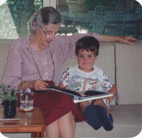 Mom on the left reading to Jimmy. Her head is down. She's wearing a striped button shirt and a maroon skirt. Jimmy is wearing Buzz Lightyear pajamas and is looking at the camera.