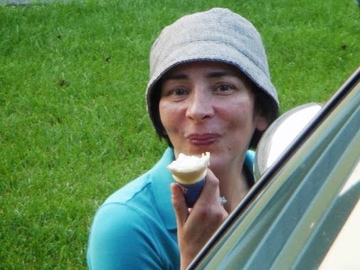 Donna wearing a turquoise colored shirt and a gray bucket hat eating vanilla ice cream cone in a game