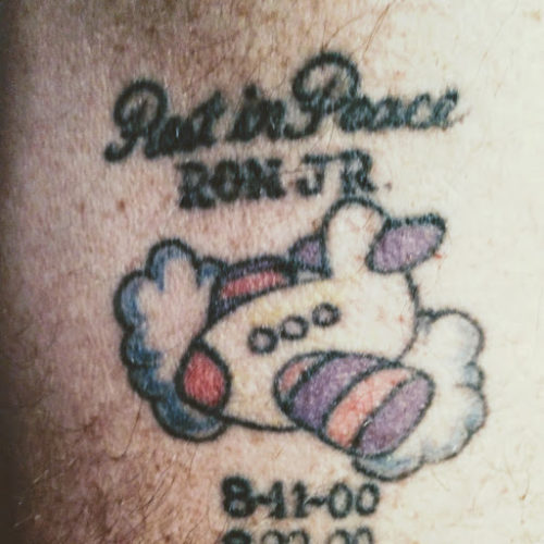 Ron's tattoo in honor of his son, Ron Jr. The words "Rest in Peace" are over "RON JR." which is over a childlike drawing of an airplane. The date 8-11-00 is under the plane with 8-- --00 below that