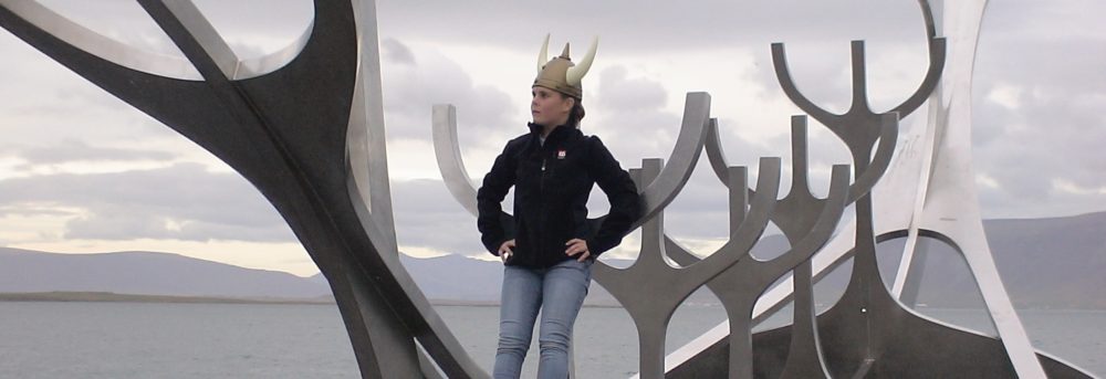 Molly standing on the Viking Ship statue in Reykjavik . She's wearing a Viking hat, black jacket and blue jeans