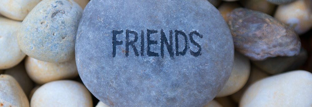 The word FRIENDS written on a flat gray rock sitting on a pile of rocks